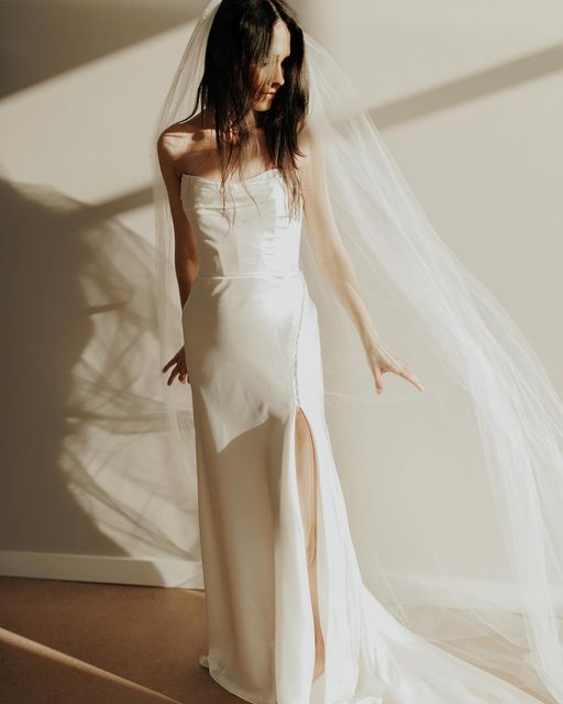 a woman in a white wedding dress posing for the camera with her veil over her head