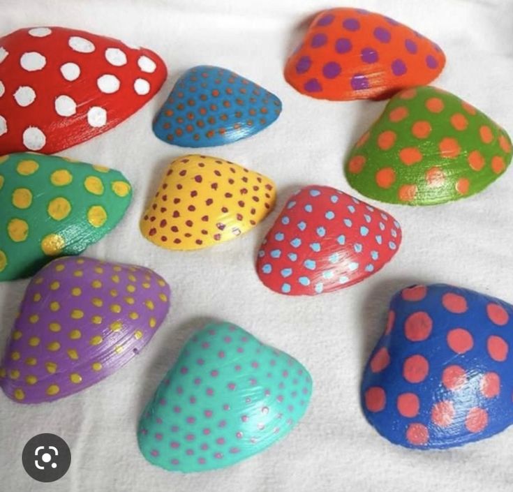 colorful polka dot painted rocks arranged in a circle on a white surface, with one laying next to each other