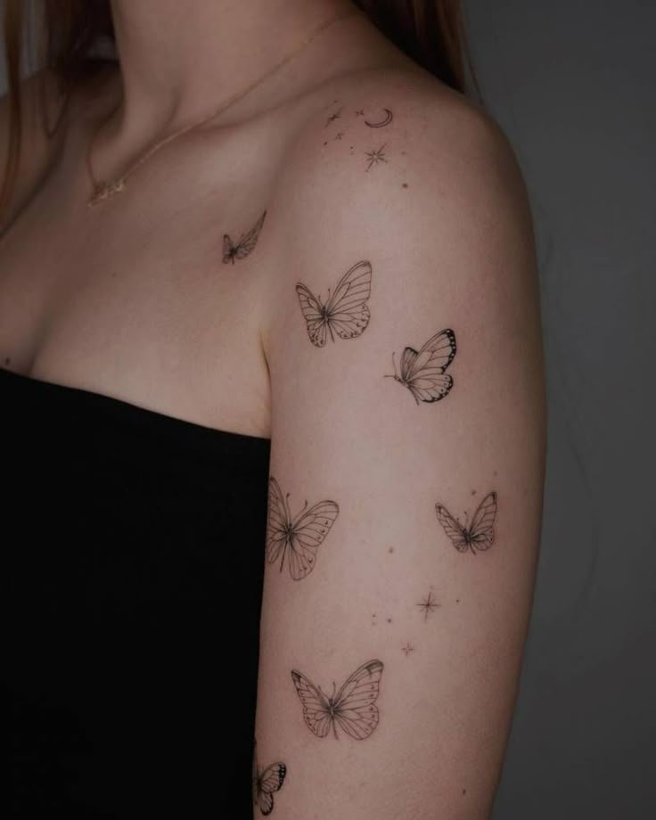 a woman's arm with butterflies and stars tattooed on the back of her shoulder