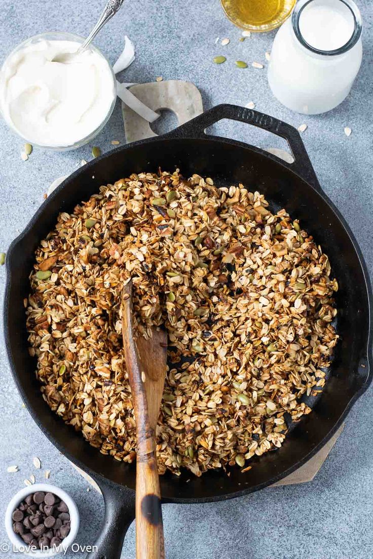 a skillet filled with granola and chocolate chips next to a glass of milk