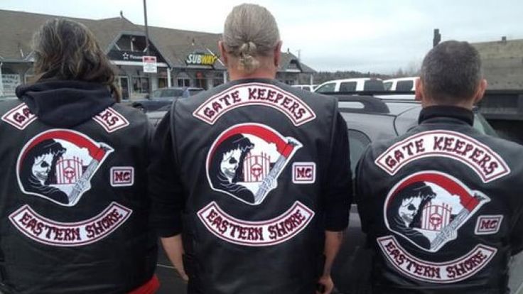 three people in black leather jackets are standing next to a car and looking at the street