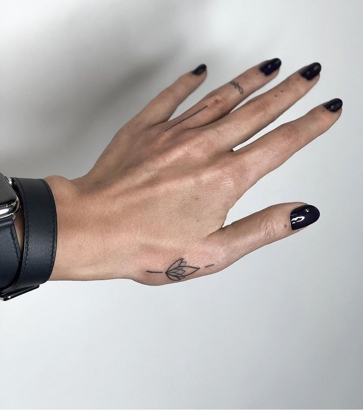 a woman's hand with black and white tattoos on her left wrist, wearing a leather bracelet