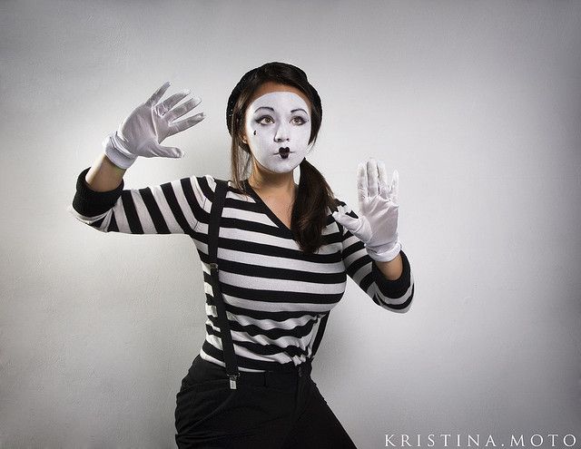 a woman dressed as mime with white makeup and black gloves on her face is posing for the camera