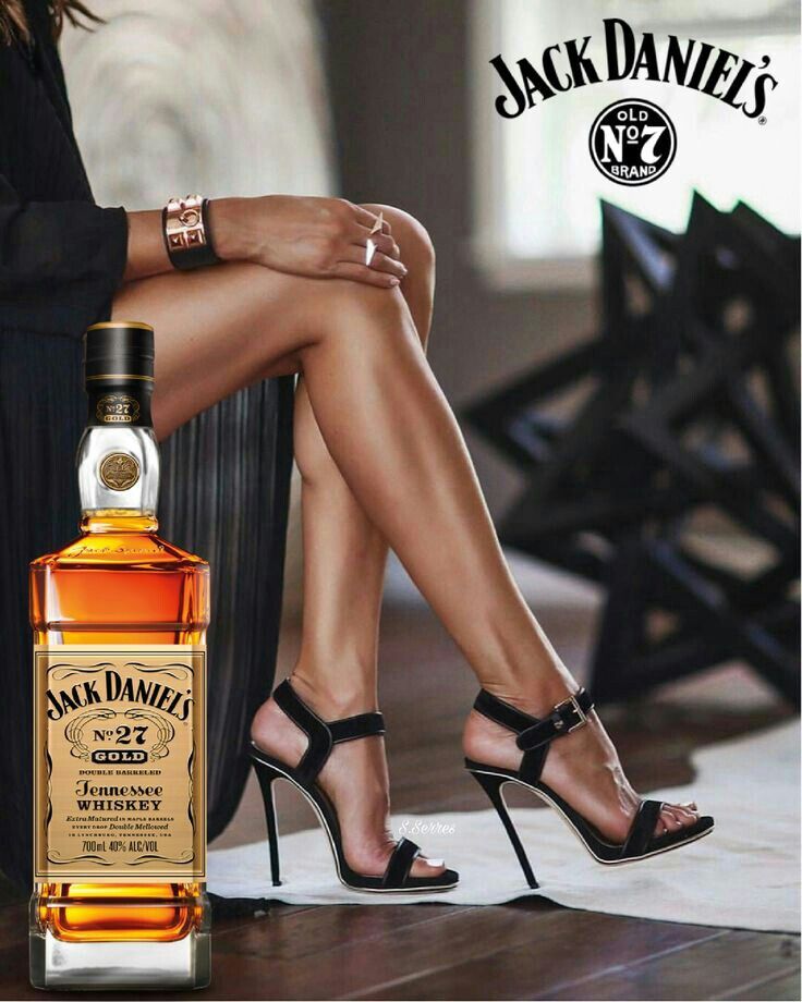 a woman in high heeled sandals sitting next to a bottle of jack daniels whiskey