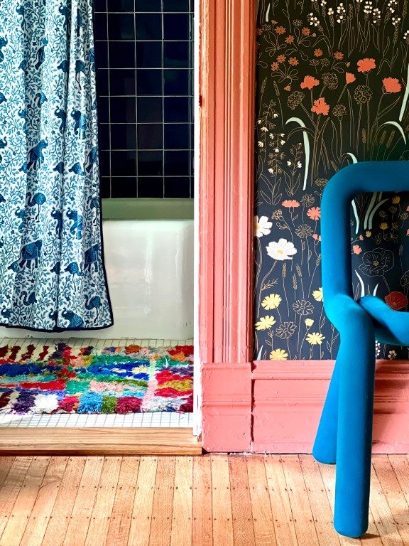 a blue chair sitting on top of a wooden floor in front of a bath tub