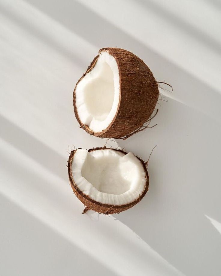 two halves of a coconut sitting on top of a white countertop next to each other