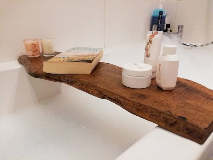 a bathtub with soaps, candles and a book on it