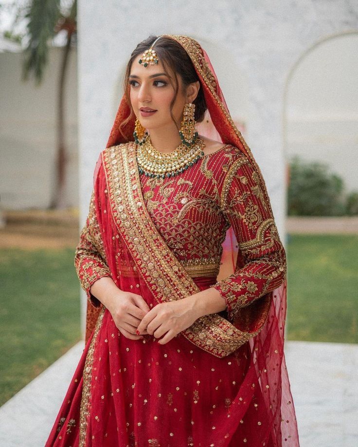 a woman in a red bridal outfit posing for the camera with her hands on her hips