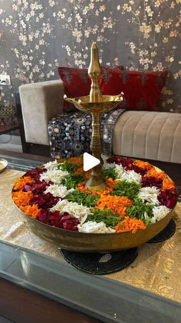 a table topped with a gold plate covered in flowers and greenery next to a couch