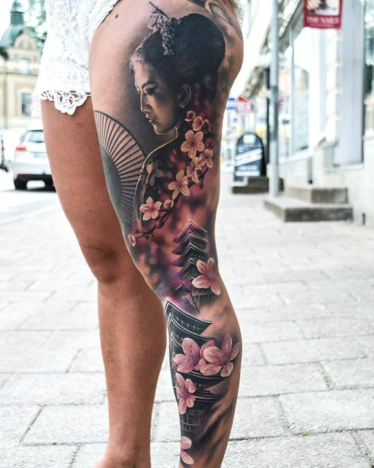 a woman's leg with tattoos on it and flowers in the bottom part of her body