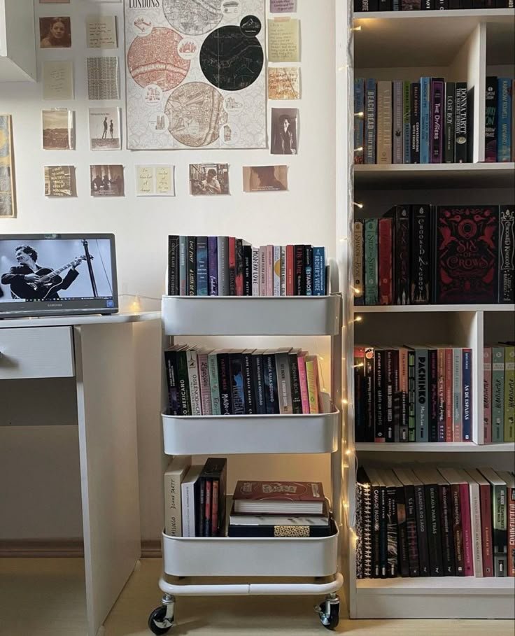 a laptop computer sitting on top of a white book shelf next to a bookshelf