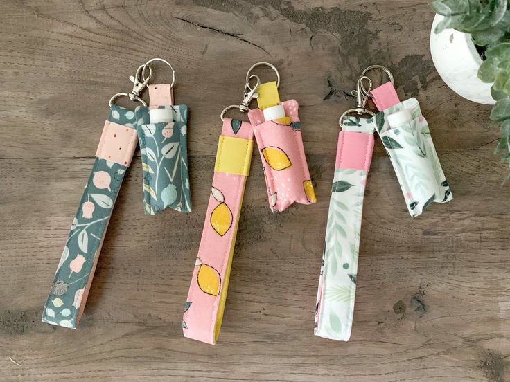 four different types of key chains on a wooden table next to a potted plant