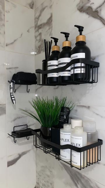 two black shelves with soaps, lotions and plants on them in a bathroom