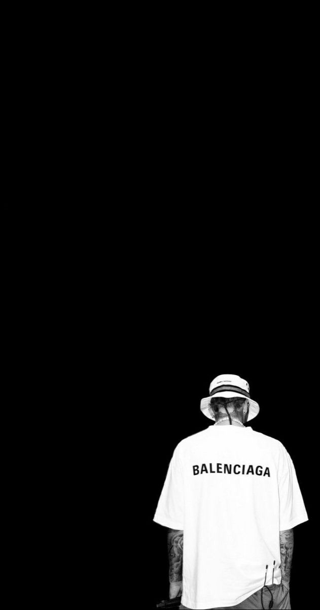 a man wearing a hat and t - shirt standing in front of a black background