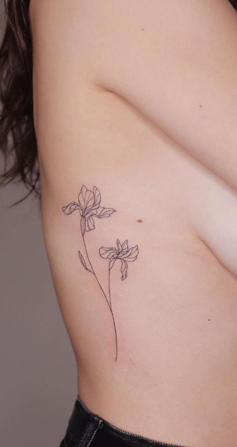 a small flower tattoo on the back of a woman's left side ribcage