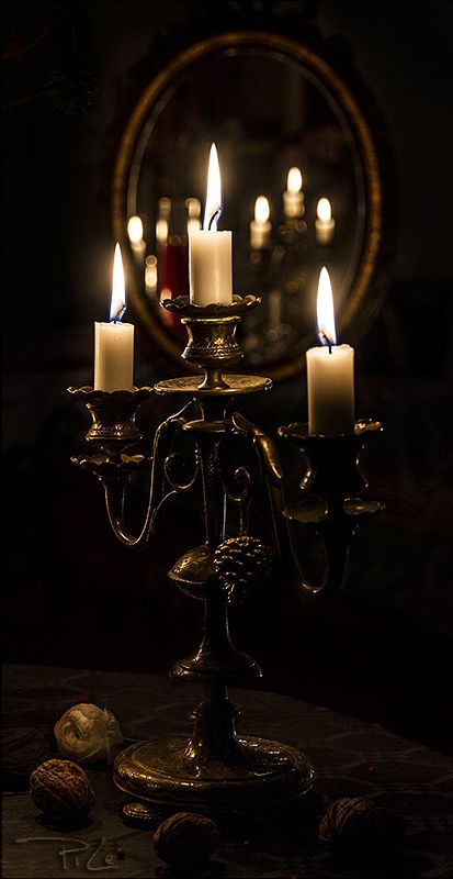 a candle holder with five lit candles in the dark, surrounded by other items on a table