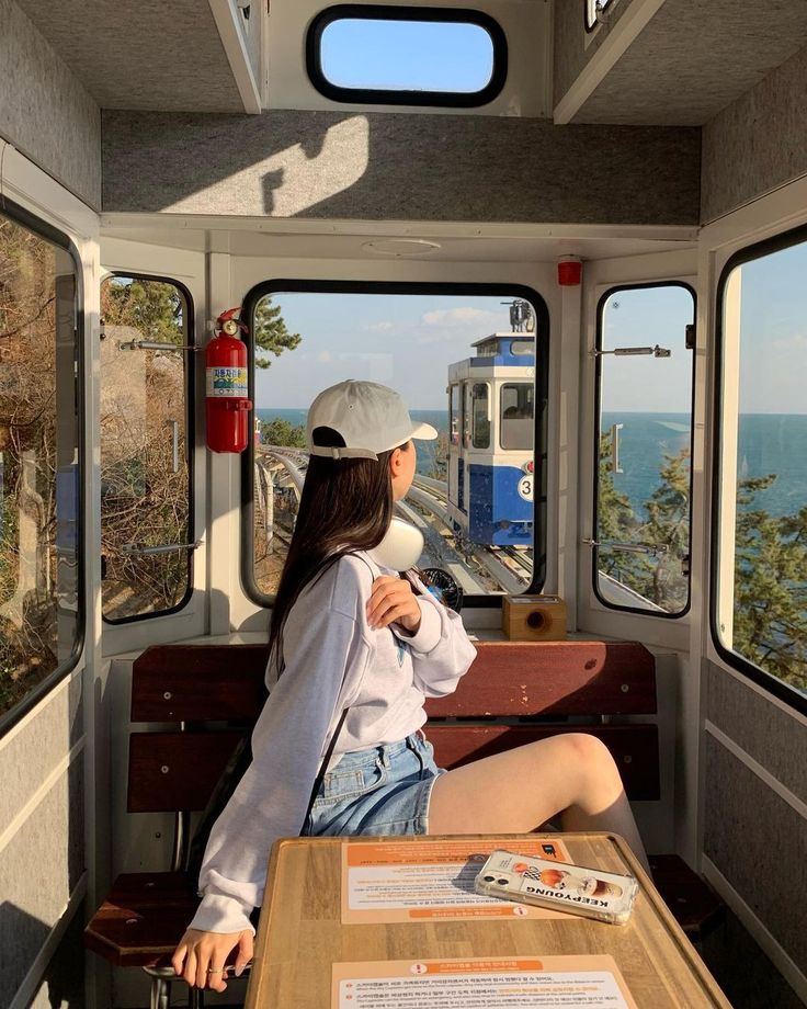 a woman sitting at a table in the back of a bus looking out over the ocean