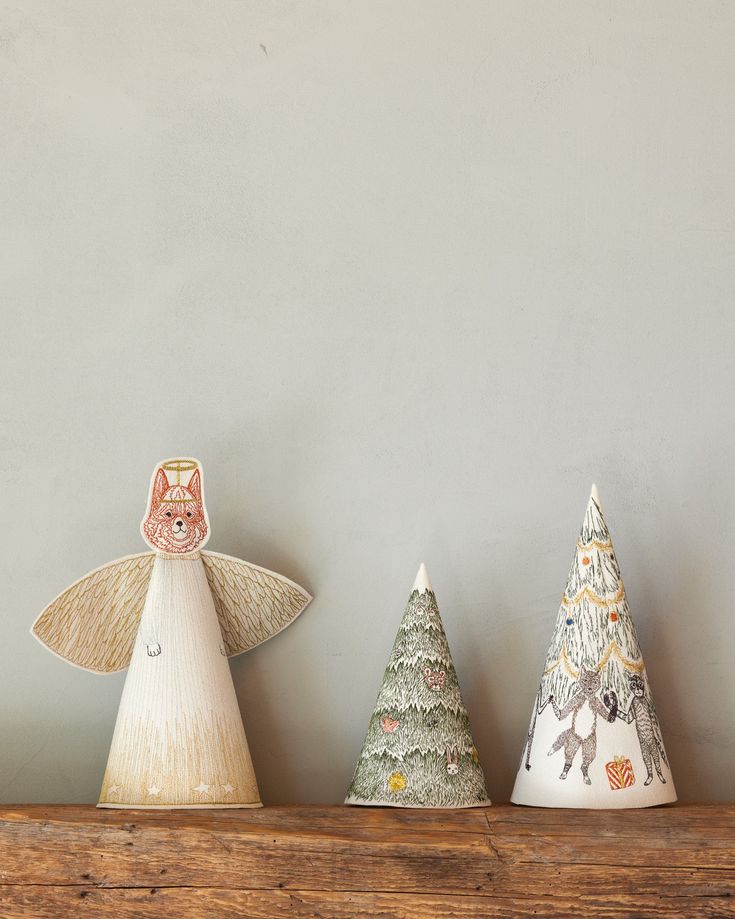 three small christmas trees sitting on top of a wooden shelf