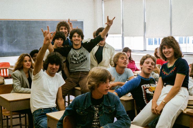 a group of people sitting at desks in a classroom with one person raising his hand