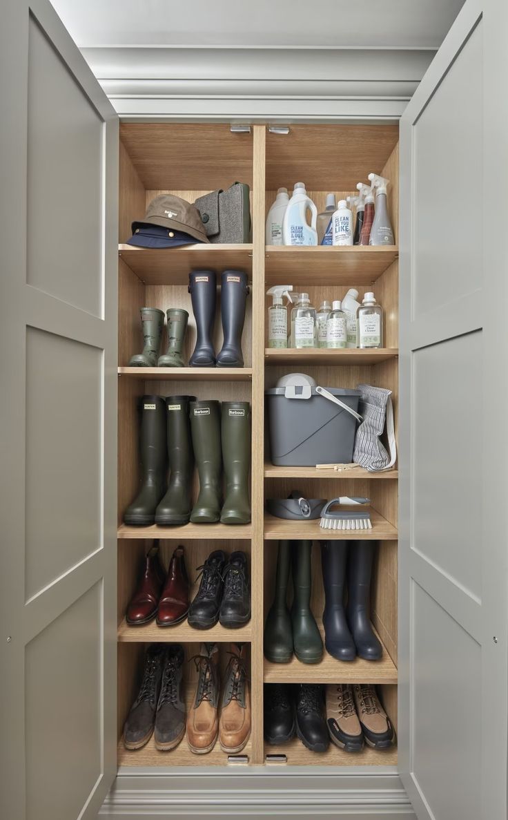 an open closet filled with lots of shoes and cleaning supplies on shelves next to doors