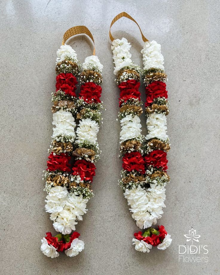 two red and white flowers are attached to some kind of thing on the floor in front of a wall