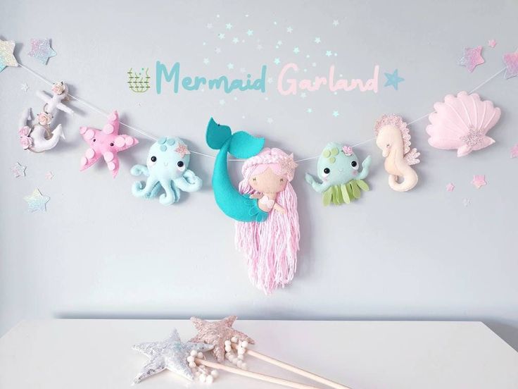 there is a mermaid garland on the wall with little sea creatures hanging from it's sides