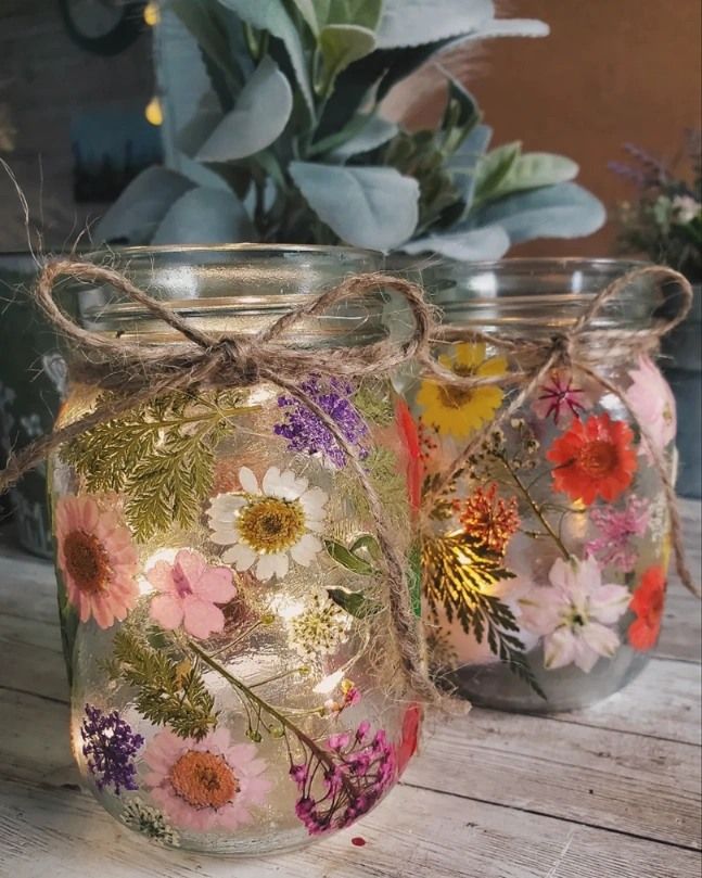 three mason jars with flowers painted on them and twine tied to each other, sitting on a wooden table