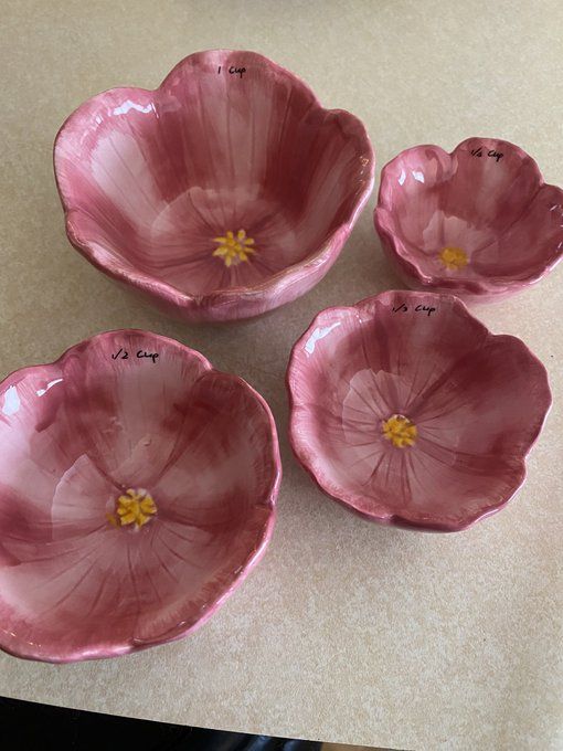 four pink flower shaped bowls sitting on top of a counter