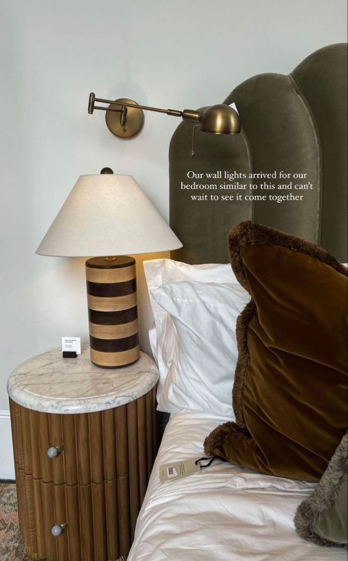 a bed with a lamp on top of it next to a night stand and pillow