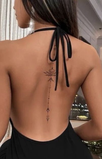 the back of a woman's dress with an arrow tattoo on it