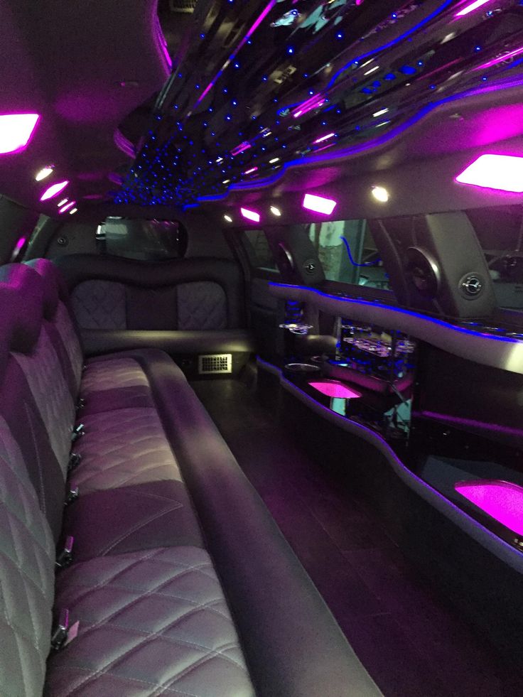 the inside of a limo with purple lights and black leather seats, all lit up