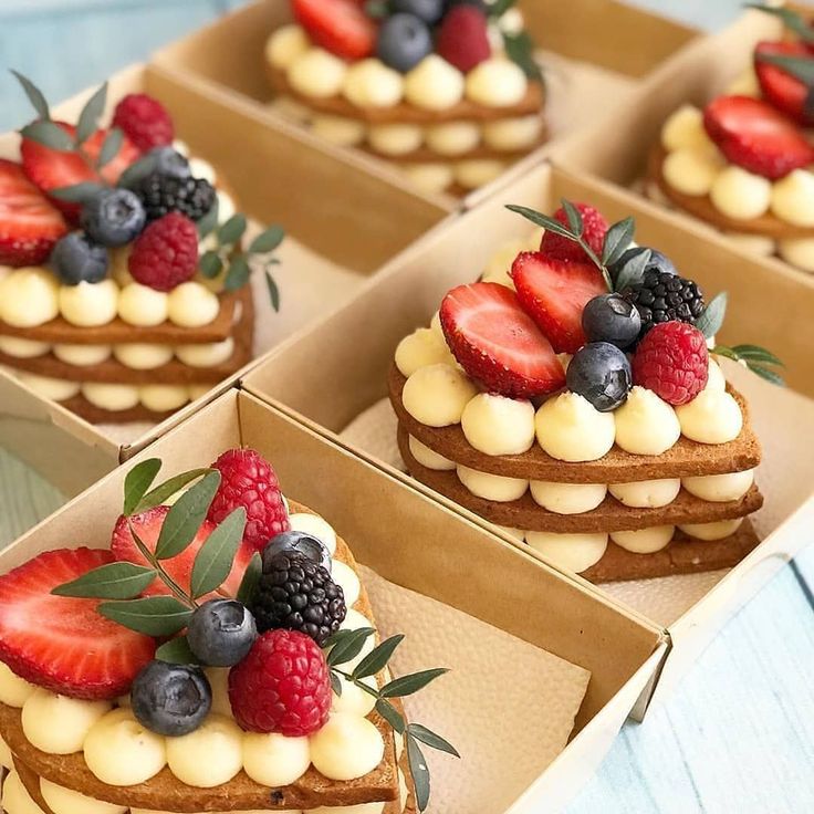 four boxes filled with different types of cakes and berries on top of each other,