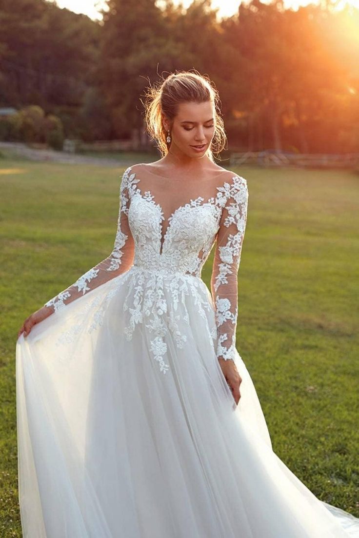 a woman in a wedding dress standing on the grass