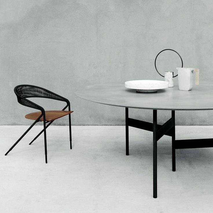 two chairs and a table in front of a concrete wall with a white plate on it