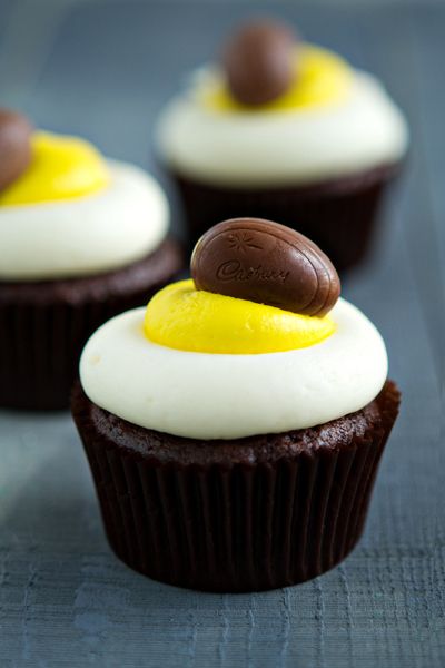 chocolate cupcakes with white frosting and yellow icing