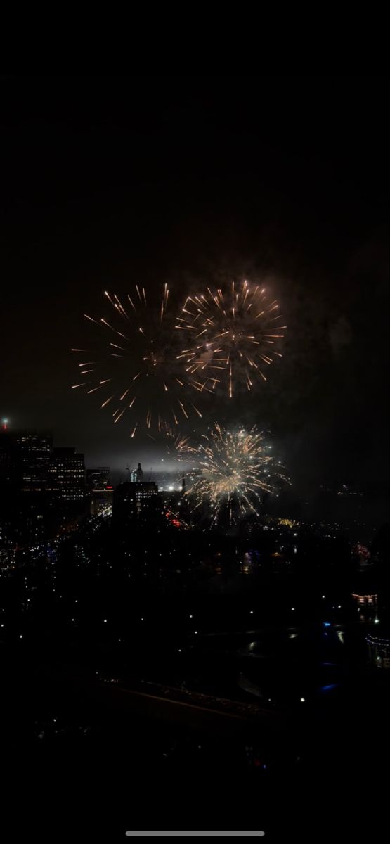 fireworks are lit up in the night sky above a cityscape with skyscrapers