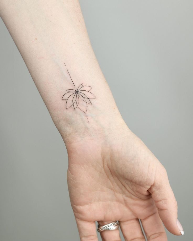 a woman's hand with a small flower tattoo on her left arm and wrist