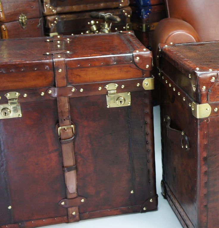 two brown trunks sitting next to each other on top of a white floor covered in leather