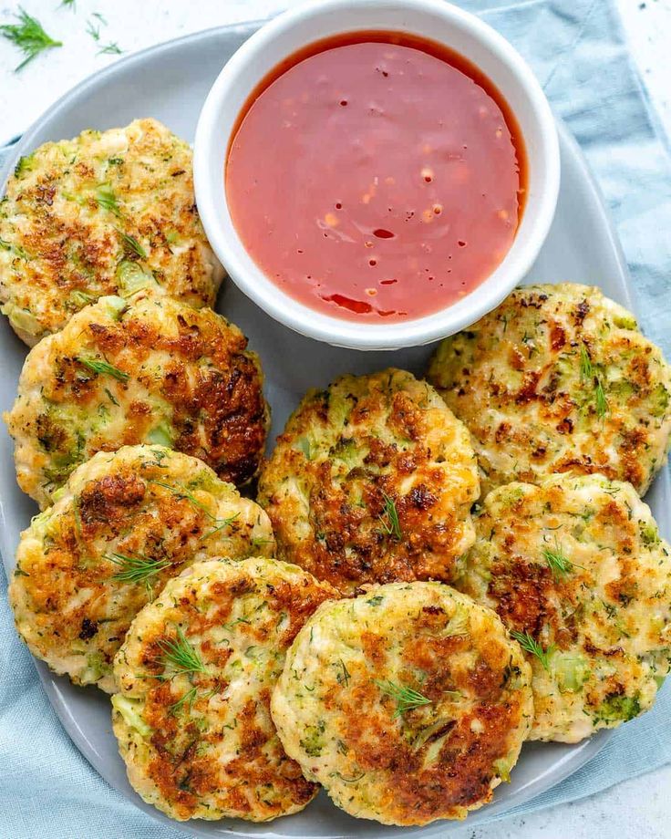 several crab cakes on a plate with dipping sauce