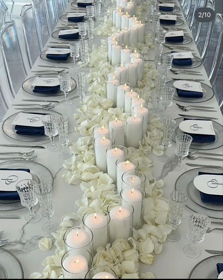 a long table with white flowers and candles on it is set for a formal dinner