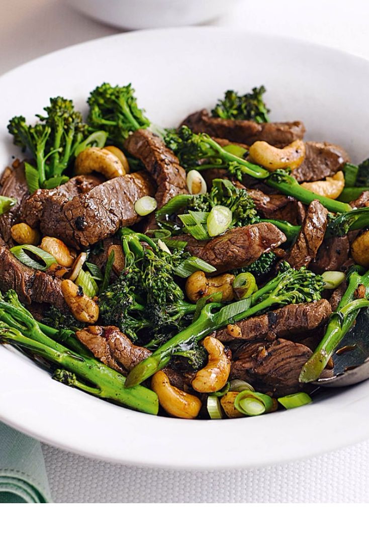 a white bowl filled with beef and broccoli