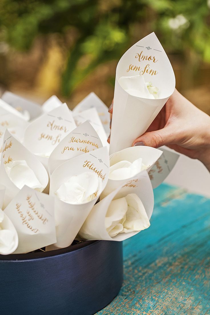 a person is holding a paper cone with flowers in it on a blue table outside