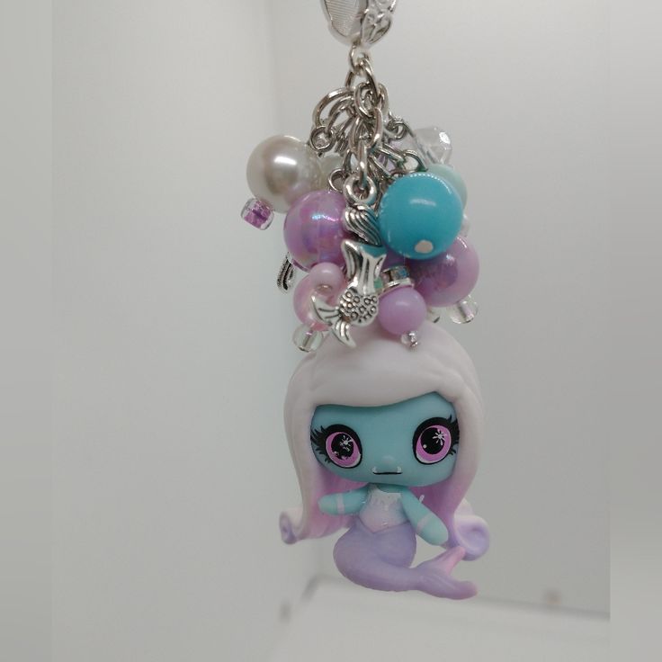 a key chain with an adorable little doll on it's head and lots of balloons attached to it