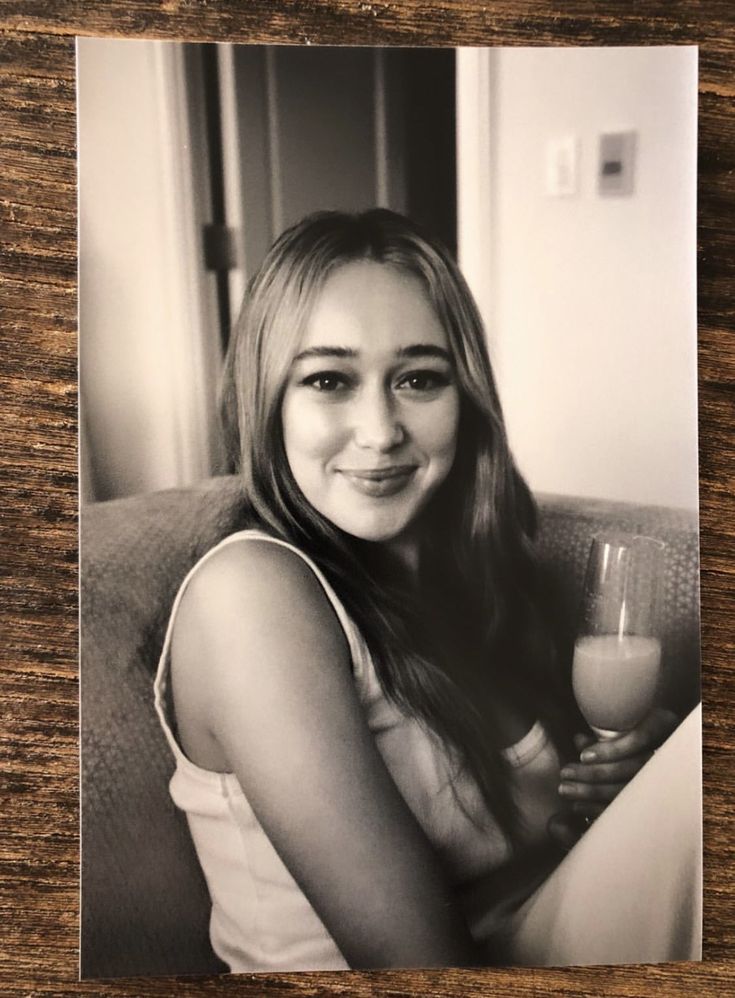 a black and white photo of a young woman holding a glass of wine in her hand