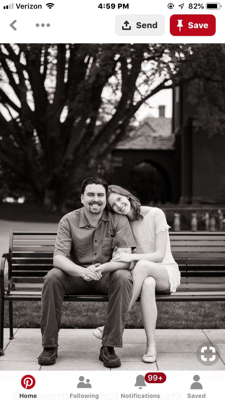 a man and woman sitting on a bench in front of a tree with their arms around each other