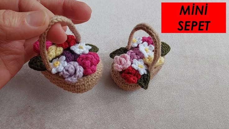 small crocheted basket with flowers on it being held by someone's hand