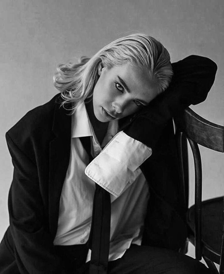 a black and white photo of a woman sitting in a chair with her hand on her face