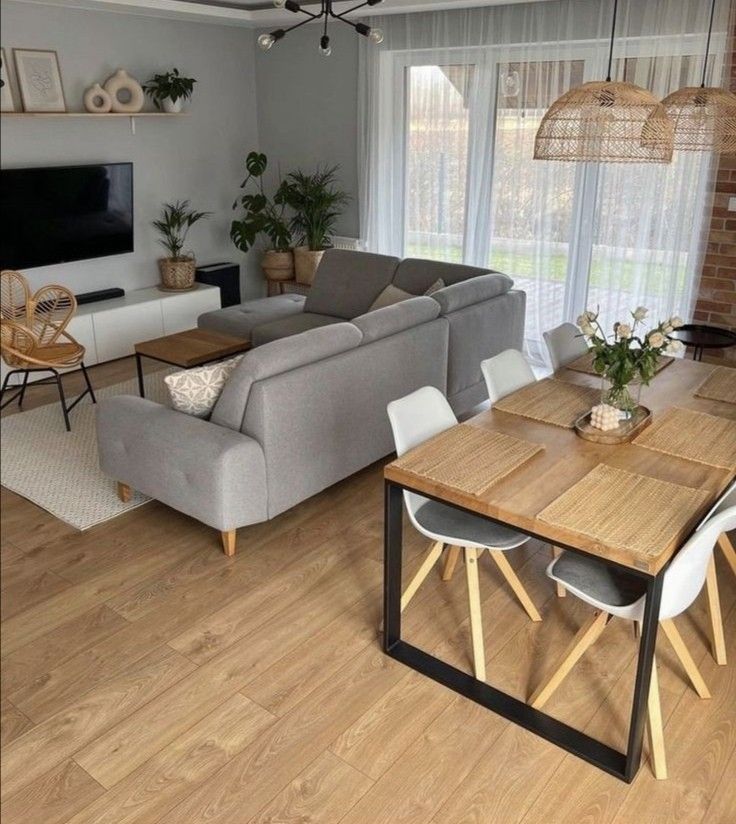 a living room filled with furniture and a flat screen tv mounted to a wall above a wooden dining table