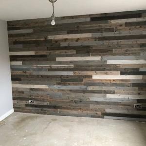 an empty room with wood planks on the wall and a light fixture hanging from the ceiling