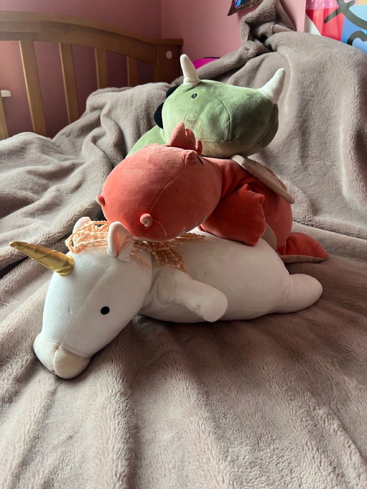 two stuffed animals sitting on top of a bed